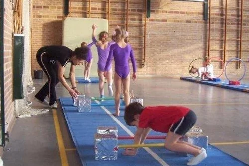 Kinder- en gezinscoach Fiona als vakleerkracht toen, begeleidt de oudste kleuters tijdens hun eerste gymlessen met echte gymtoestellen in de grote gymzaal.